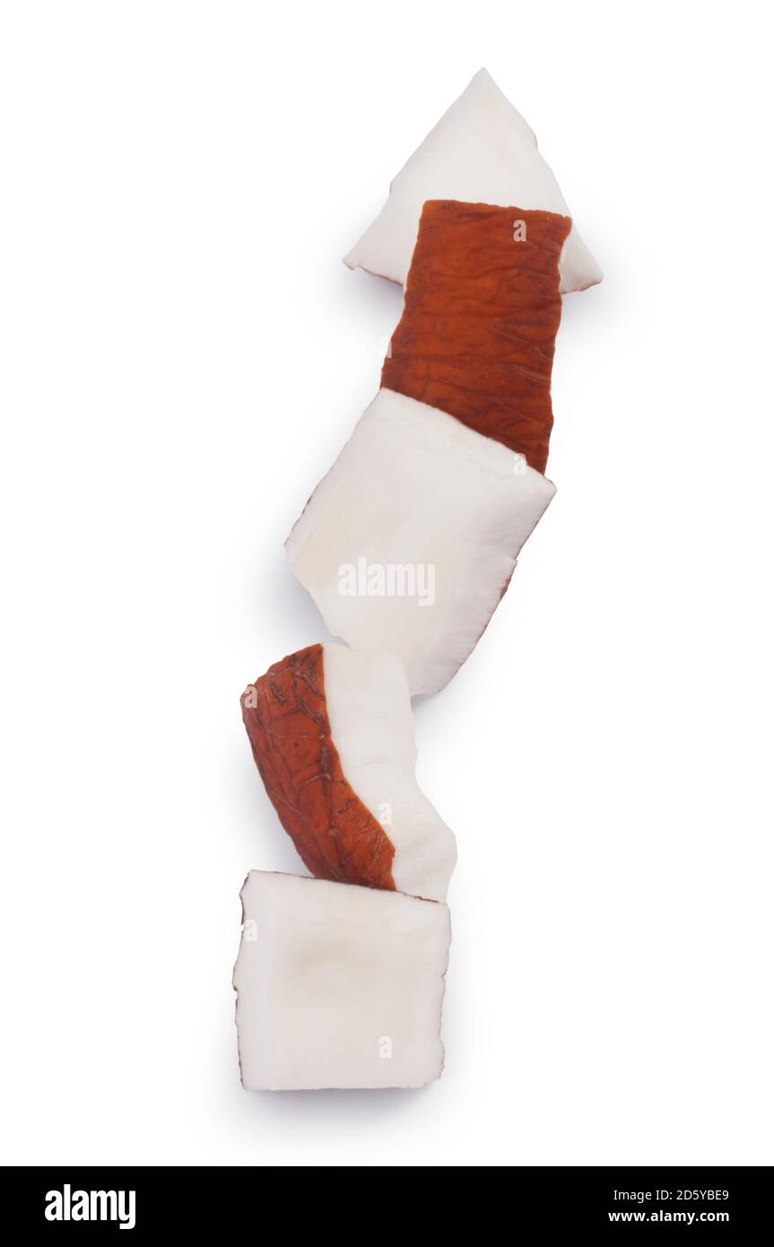 Studioaufnahme von kleinen Kokosnussstücken, gegen die es geschnitten wurde Ein weißer Hintergrund - John Gollop Stockfoto