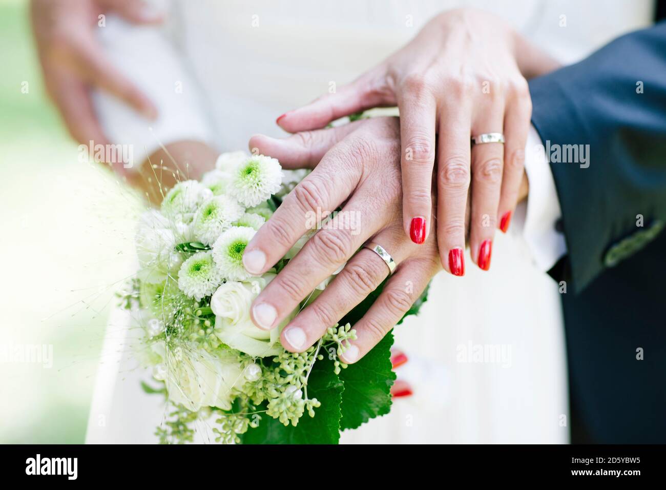 Braut und Bräutigam zeigen Eheringe, halten Bouquet Stockfoto