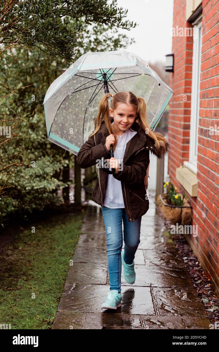 Portrait von lächelndes Mädchen mit Regenschirm an regnerischen Tag Stockfoto