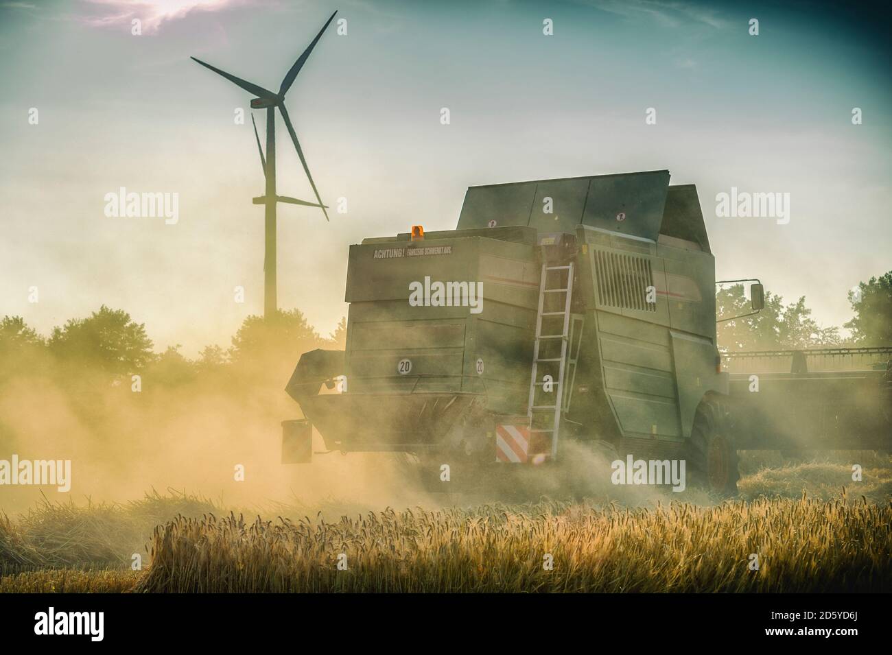 Deutschland, Grevenbroich, Mähdrescher auf Feld und Wind turbine Stockfoto