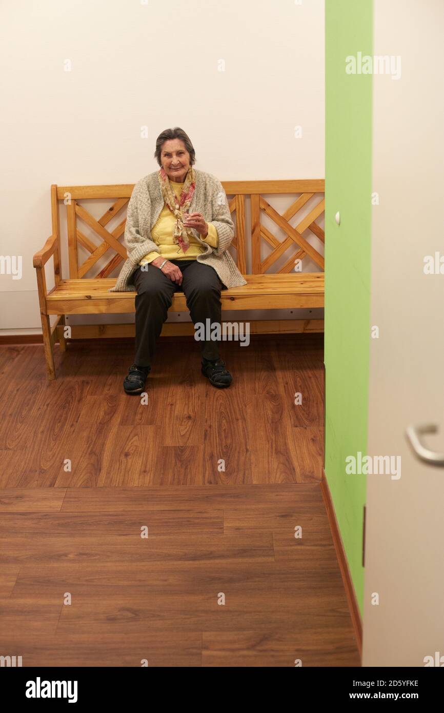 Alter demente Senioren Frau sitzen auf Bank in einem Pflegeheim Stockfoto