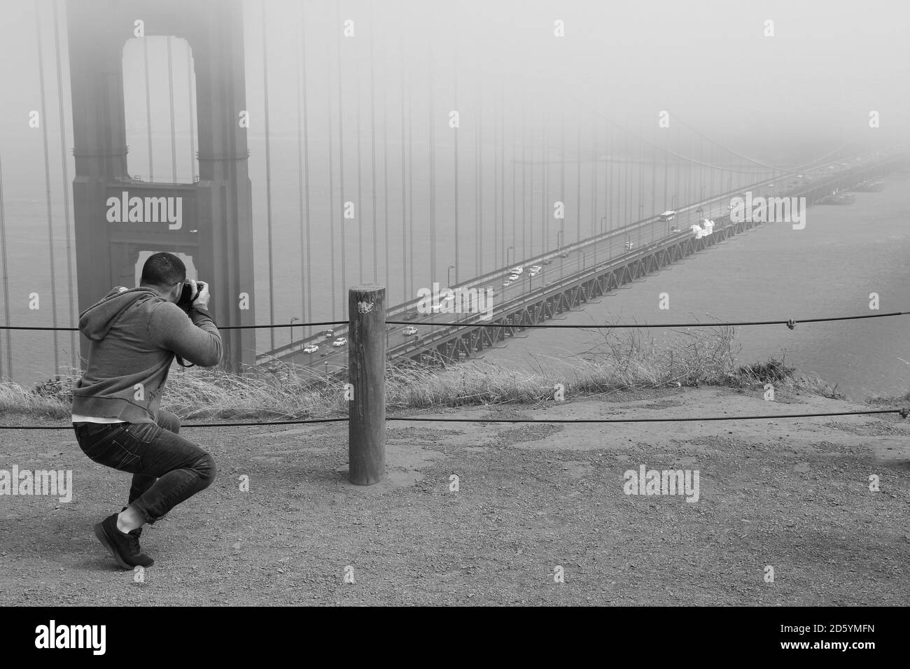 Graustufenaufnahme eines Mannes, der die Golden Gate Bridge fotografiert Stockfoto