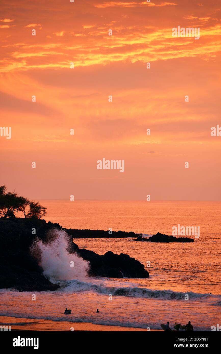 USA, Hawaii, Big Island, Hapuna Beach, Sonnenuntergang an der Kohala Coast mit brandende Woge und Menschen Baden Stockfoto