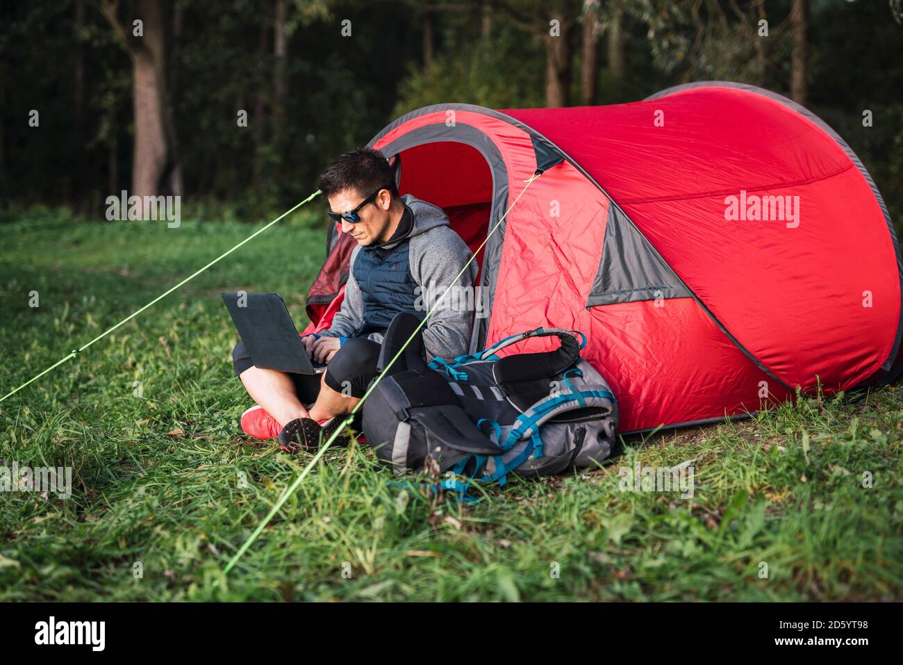 Mann, der in Estland zeltet, im Zelt sitzt, mit Laptop Stockfoto