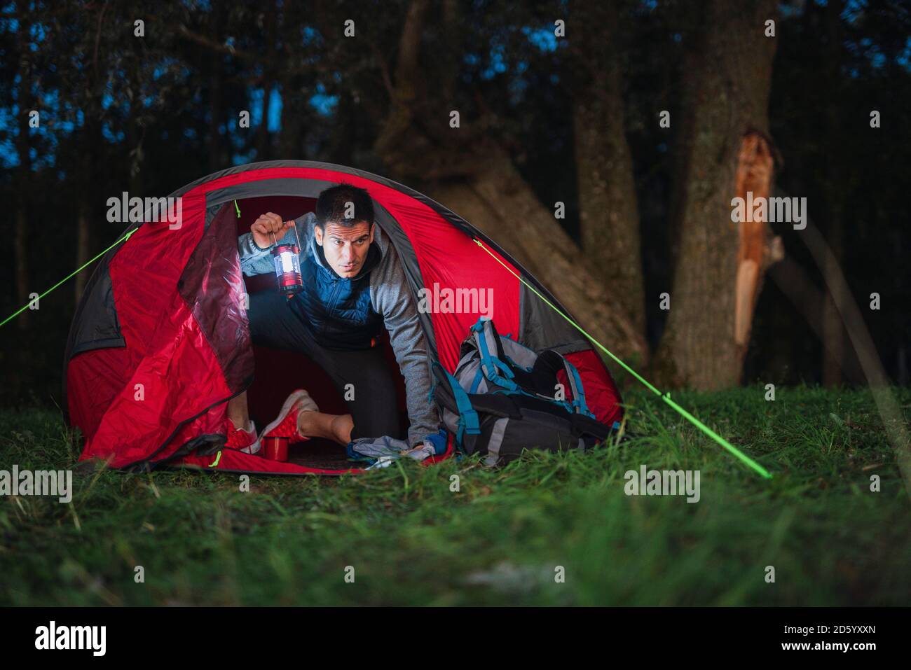 Mann, der in Estland campte, in seinem Zelt sitzend, latern haltend Stockfoto