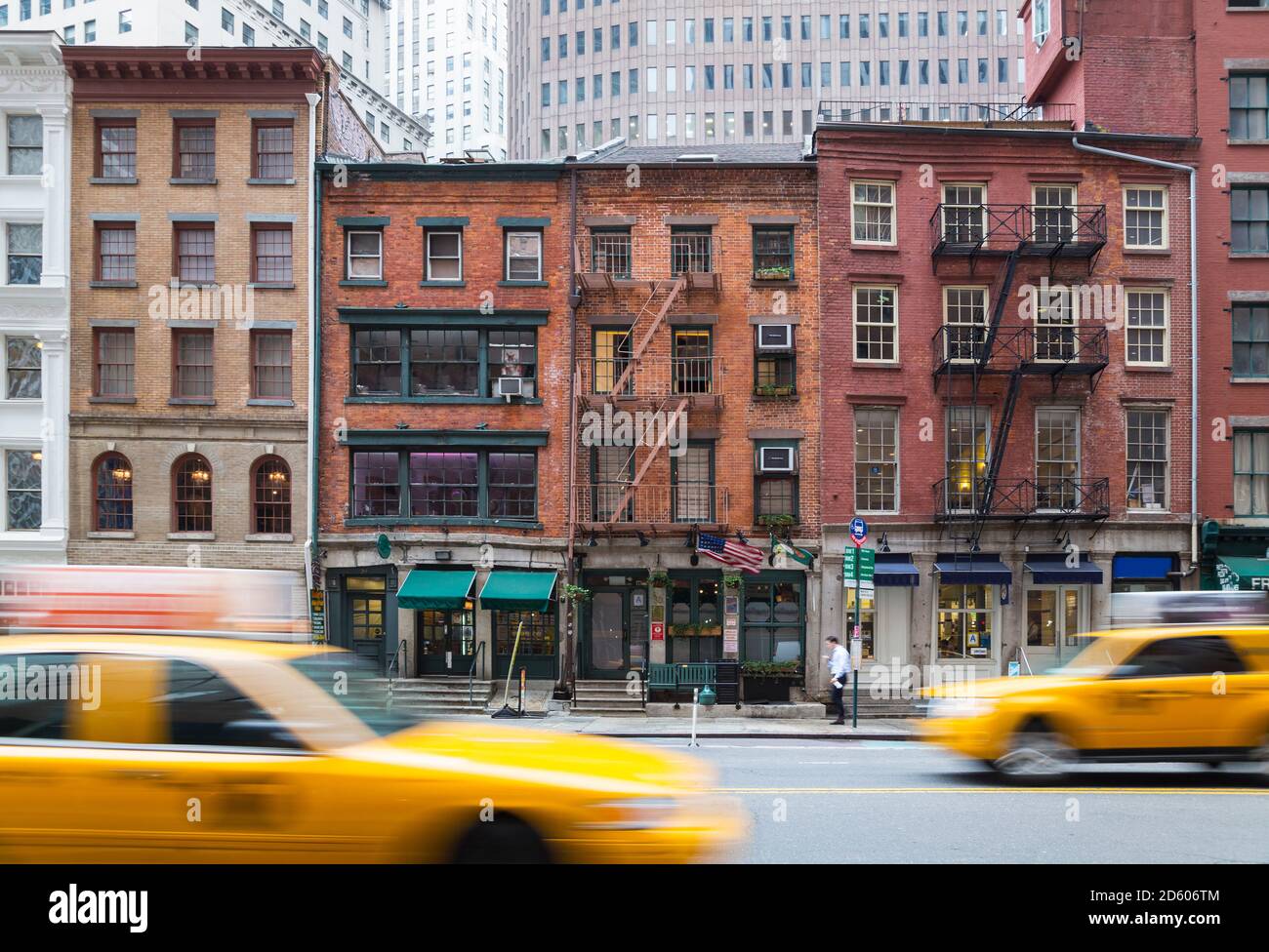 USA, New York City, Manhattan, gelbe Taxis fahren vor alten Backsteinhäusern Stockfoto