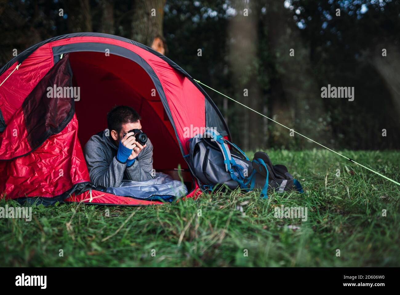 Mann, der in Estland zeltet, in seinem Zelt liegt und fotografiert Stockfoto