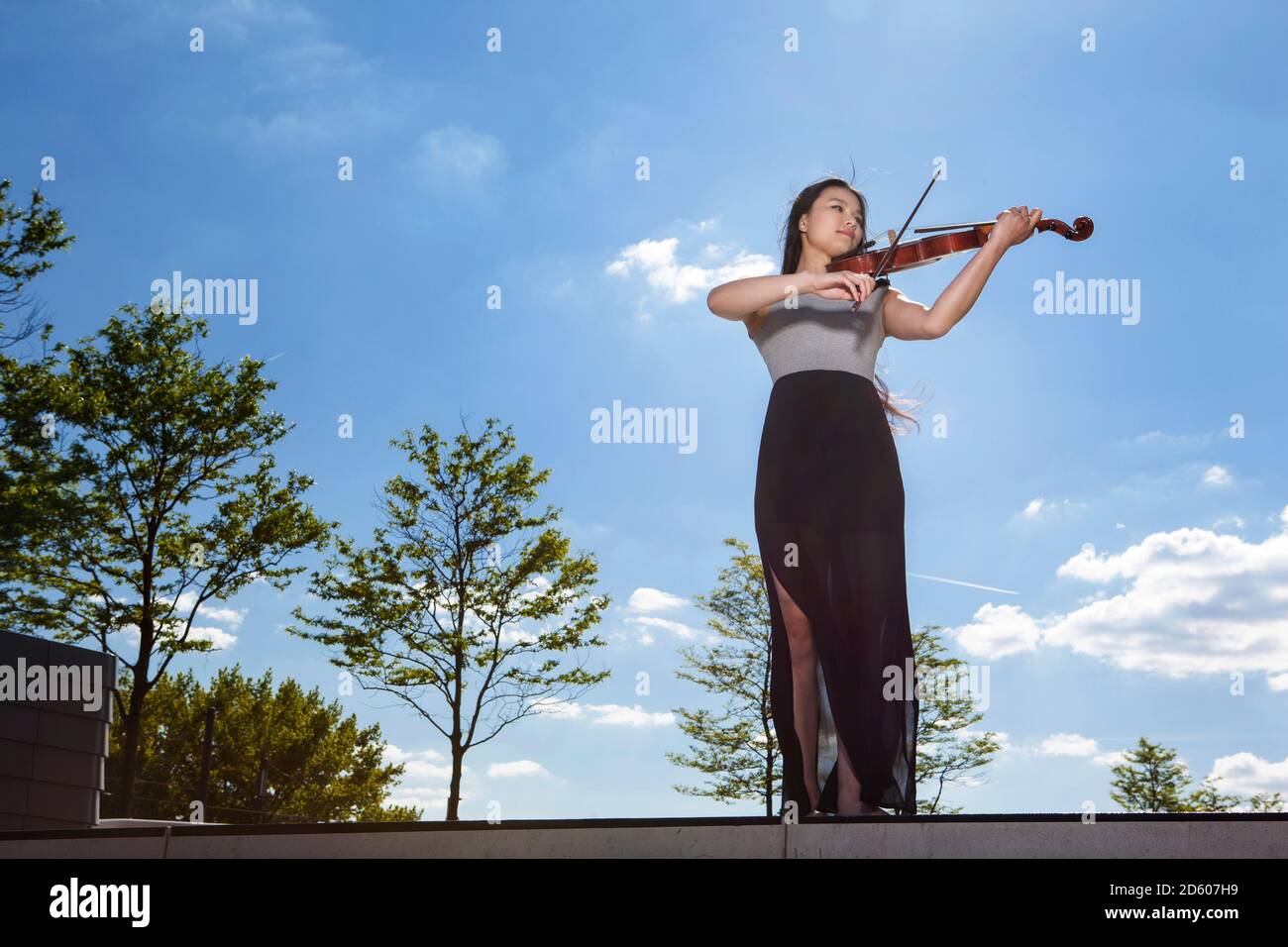 Junge weibliche asiatische spielen Geige vor Himmel Stockfoto