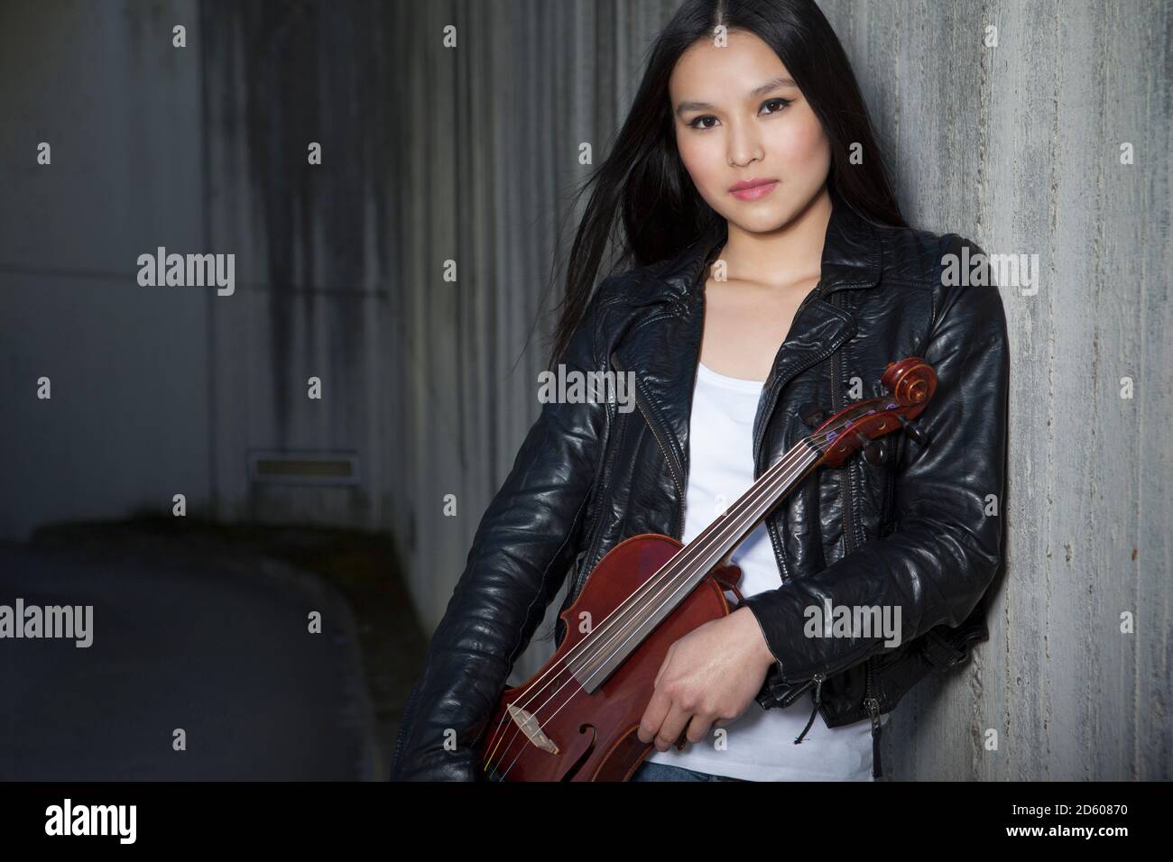 Porträt der jungen weiblichen asiatischen mit Geige an Betonwand gelehnt Stockfoto