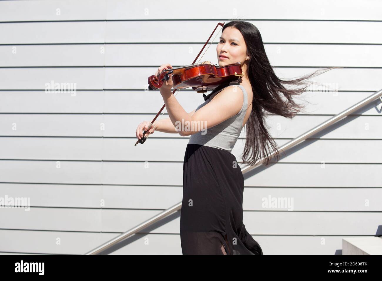 Porträt der jungen weiblichen asiatischen Geigenspiel auf Treppe Stockfoto