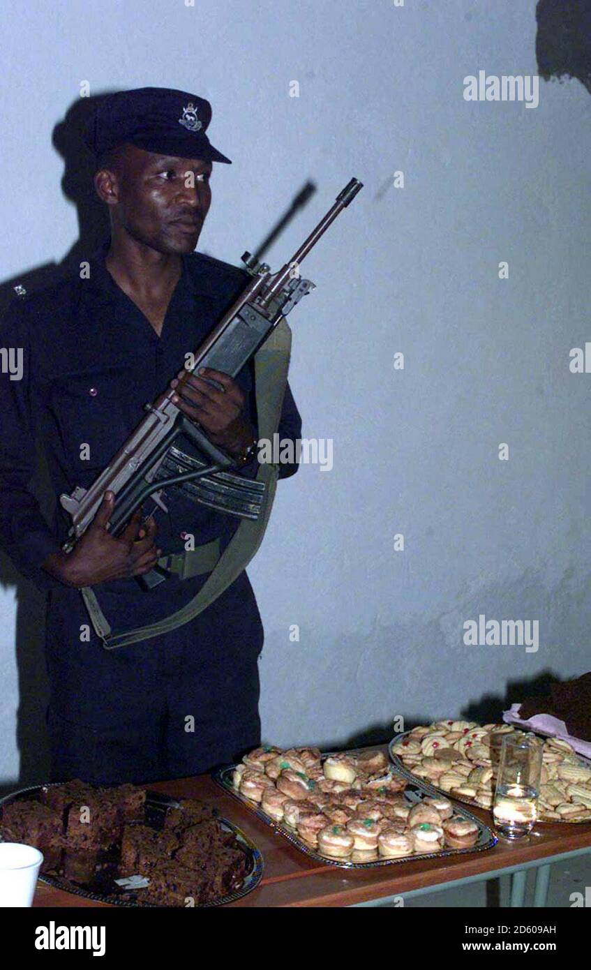 Ein Polizist, bewaffnet mit einem AK47 Gewehr, steht Wache über dem königlichen Buffet, das zu Ehren des Prinzen von Wales, der das Dorf Gundvwini im afrikanischen Bush während seiner Reise durch das südliche Afrika besuchte, ausgelegt wurde. Siehe PA Story ROYAL Africa. Foto von John Stillwell /PA. Stockfoto