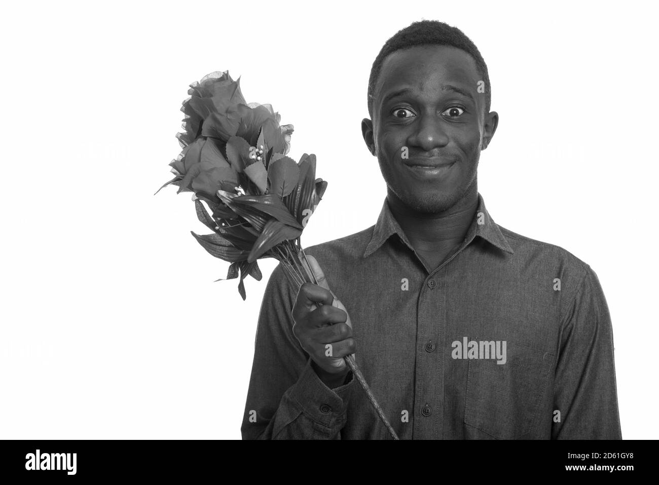 Junger glücklicher afrikanischer Mann lächelt und schaut aufgeregt beim Halten rosen bereit für Valentinstag Stockfoto