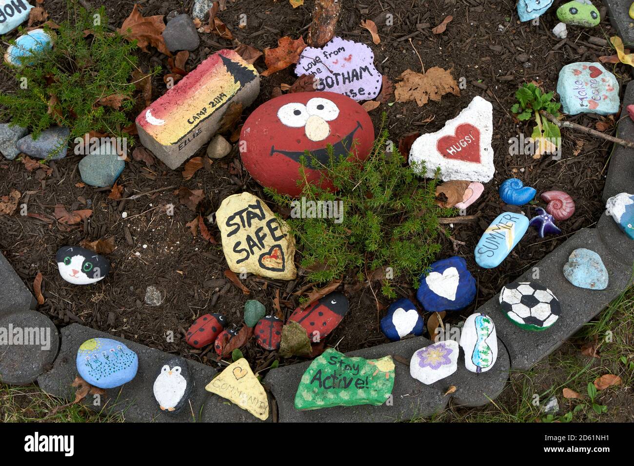 Bunt bemalte Steine mit inspirierenden Botschaften, die auf dem Boden liegen Während der weltweiten COVID-19-Pandemie Stockfoto