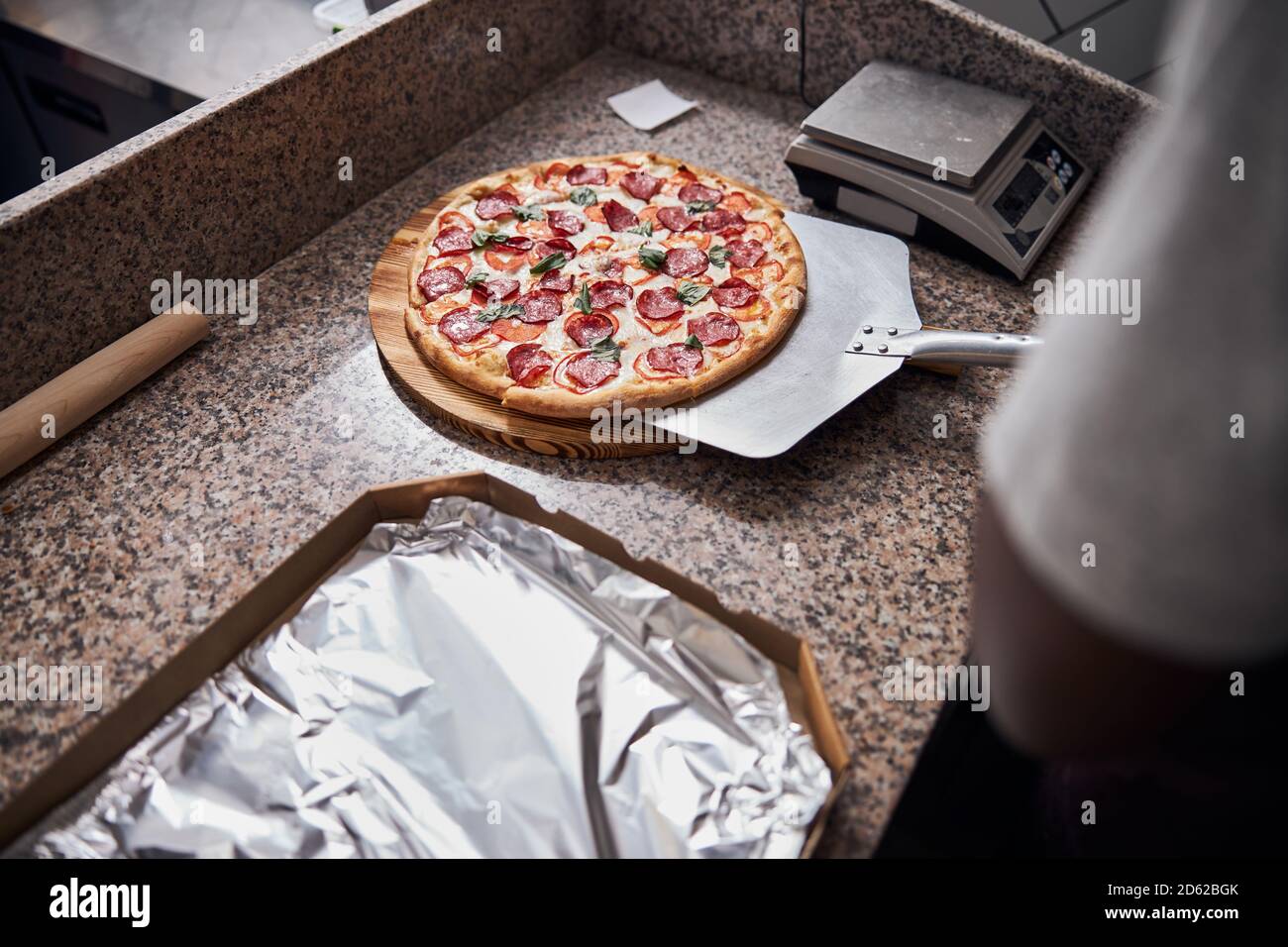 Junger Mann mit Metall Pizza Peel in der Pizzeria Stockfoto