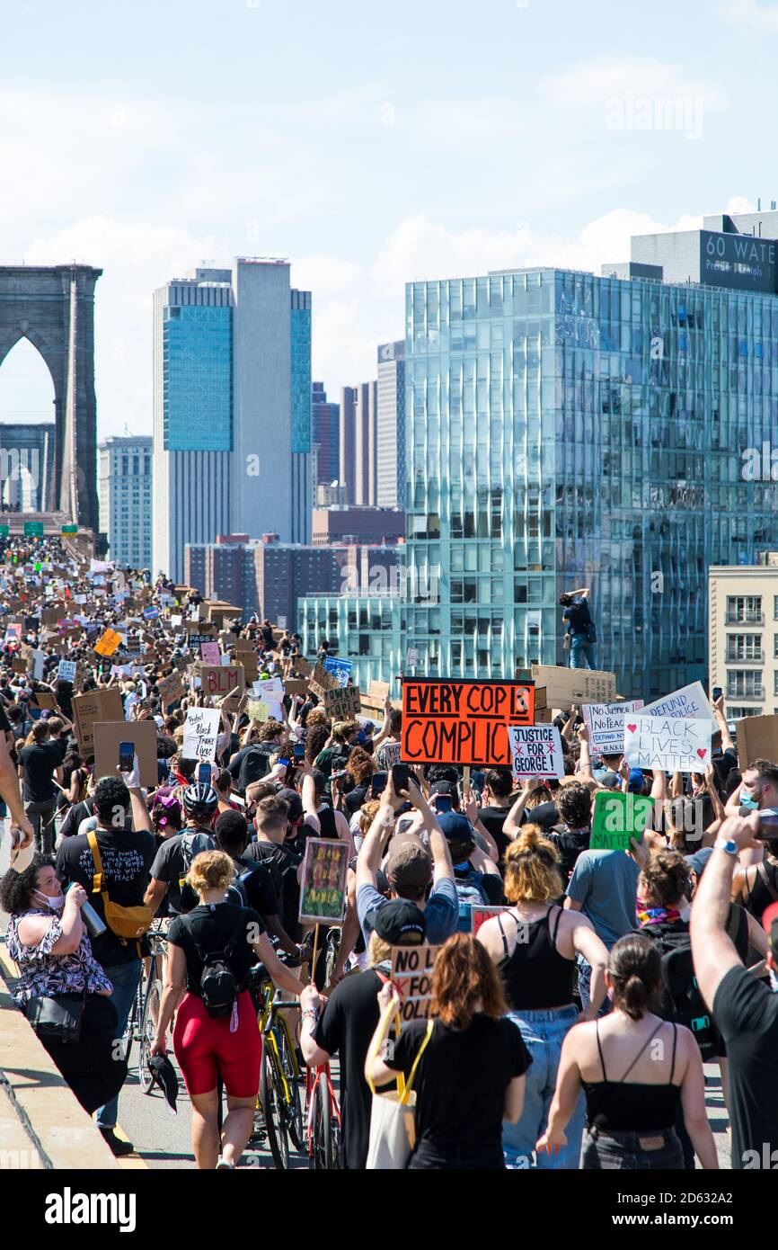 Massen von Demonstranten mit Schildern, die über die Brooklyn Bridge marschieren während des 6. März, New York City, New York, USA Stockfoto