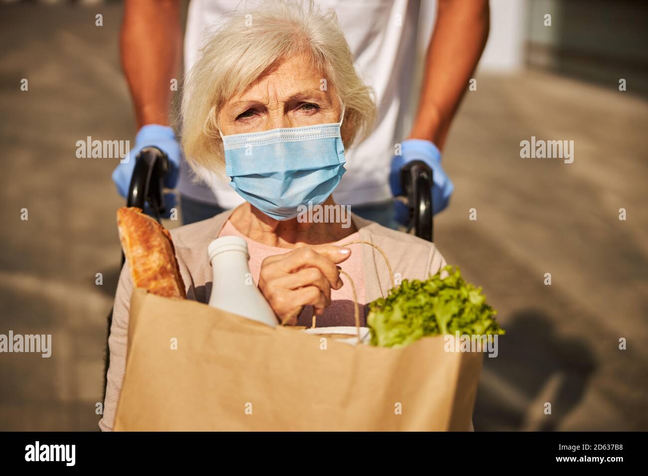 Trauriger Rentner, der ein Papierpaket mit Lebensmitteln hält Stockfoto