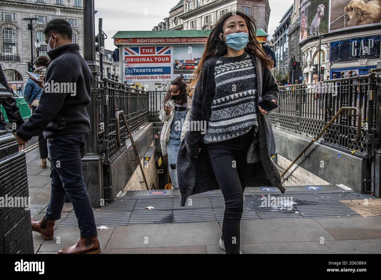 Arbeiter mit Gesichtsmasken kommen an einem Wochentag in der U-Bahn-Station Oxford Street an, um in der Oxford Street, West End, London, England zu arbeiten Stockfoto