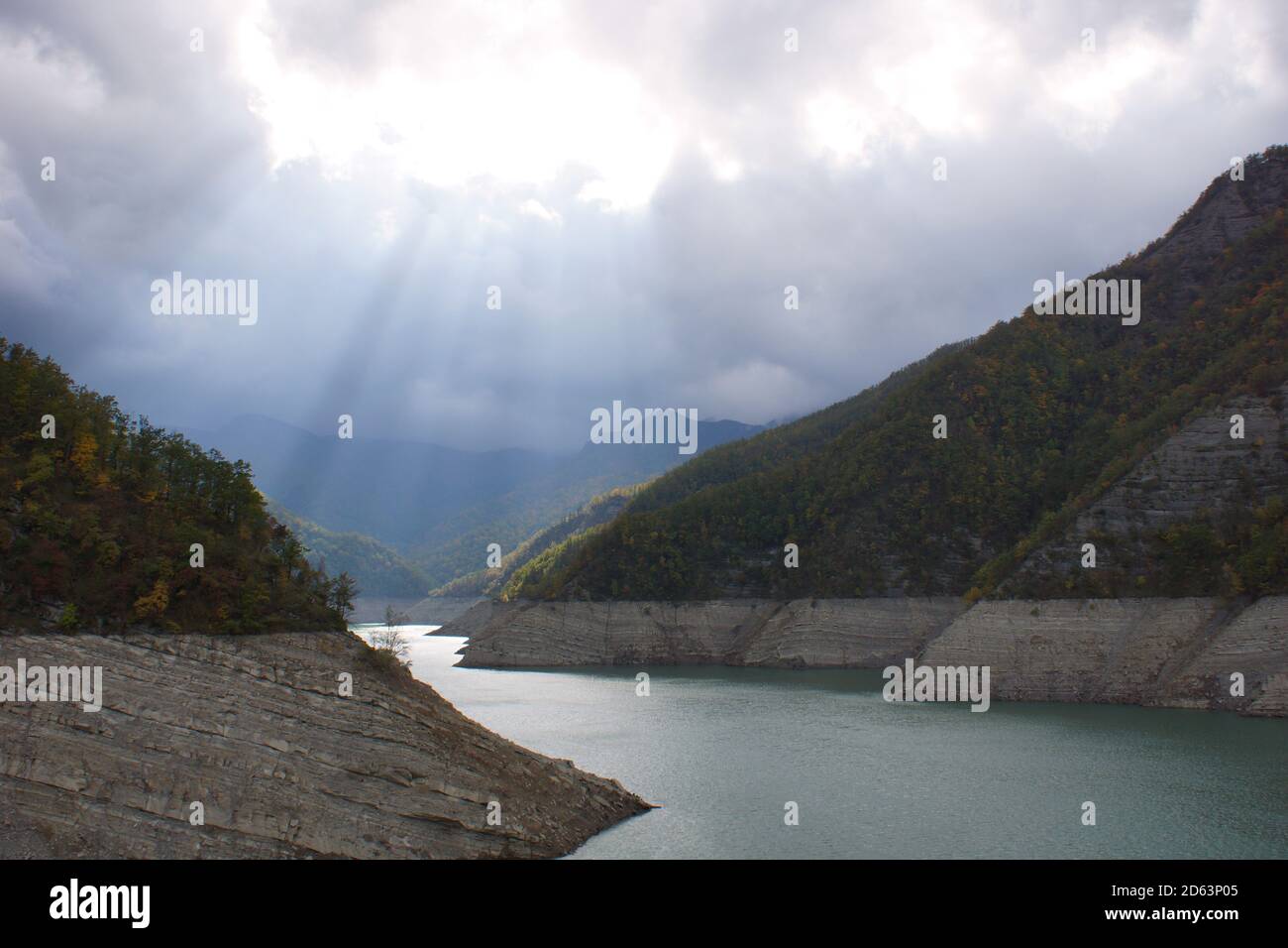 Reservoir Ridracoli. Die Sonnenstrahlen durchbrechen die Wolken und erleuchten die Berge und den See. Mountain Lake. Stockfoto