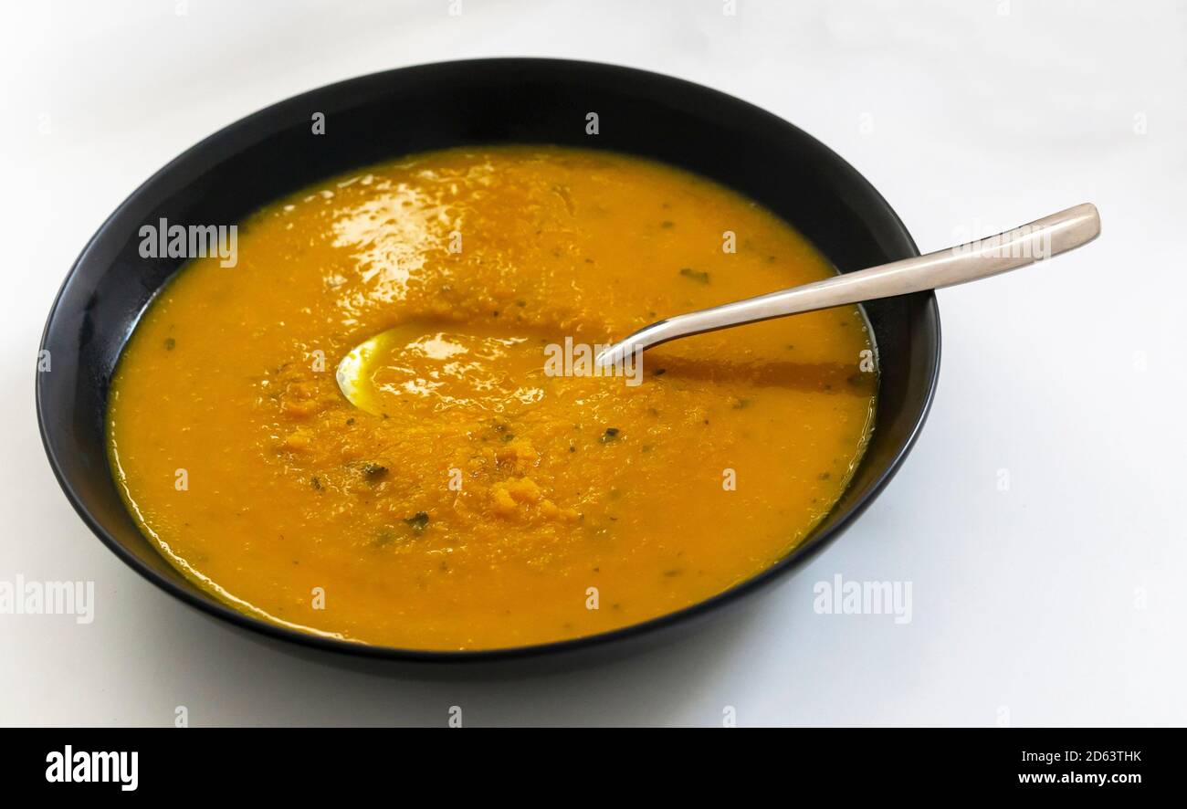 Karotten- und Koriandersuppe in einer schwarzen Schüssel Stockfoto