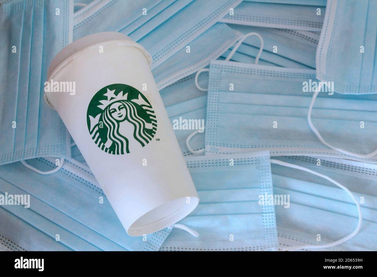 Starbucks Kaffeetasse zum Mitnehmen auf einem Hintergrund von Coronavirus Gesichtsmasken. Neue Regeln für das Öffnen nach der COVID-19-Sperre. Stockfoto