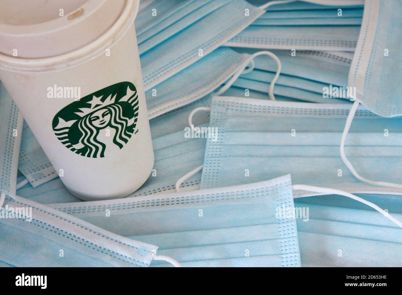 Starbucks Kaffeetasse zum Mitnehmen auf einem Hintergrund von Coronavirus Gesichtsmasken. Neue Regeln für das Öffnen nach der COVID-19-Sperre. Stockfoto