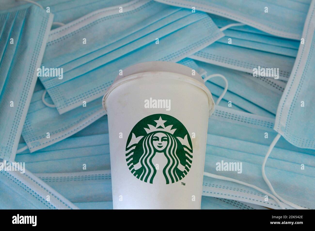 Starbucks Kaffeetasse zum Mitnehmen auf einem Hintergrund von Coronavirus Gesichtsmasken. Neue Regeln für das Öffnen nach der COVID-19-Sperre. Stockfoto