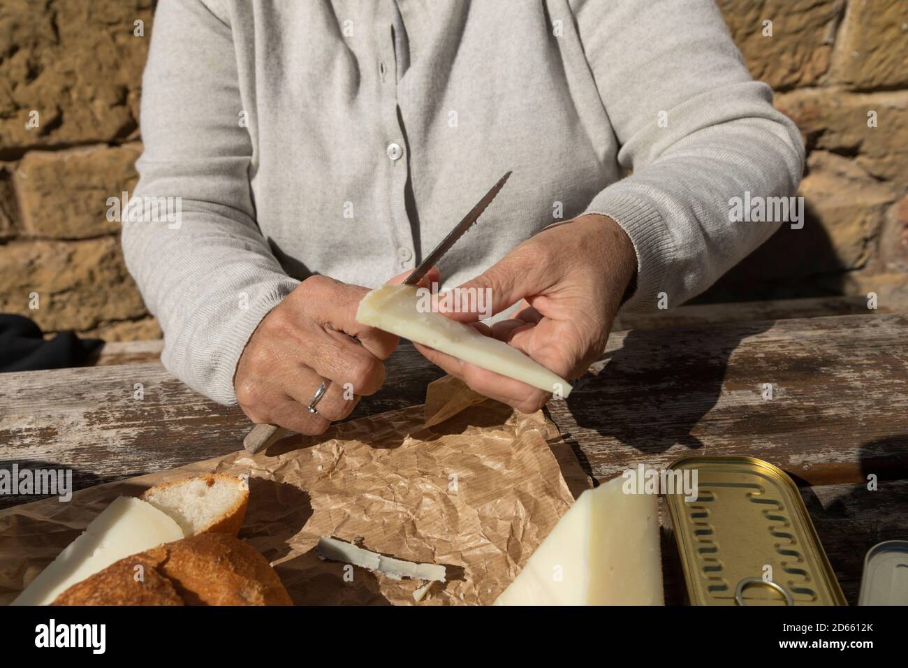 Eine ältere Frau schneidet Ziegenkäse auf der Berghütte des Brunnens von Artica in Luesia, Spanien. Stockfoto