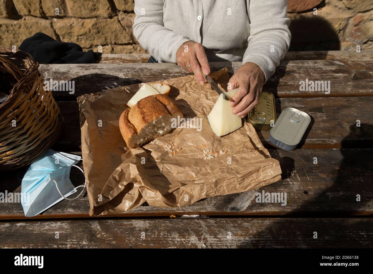 Eine ältere Frau schneidet Ziegenkäse auf der Berghütte des Brunnens von Artica in Luesia, Spanien. Stockfoto