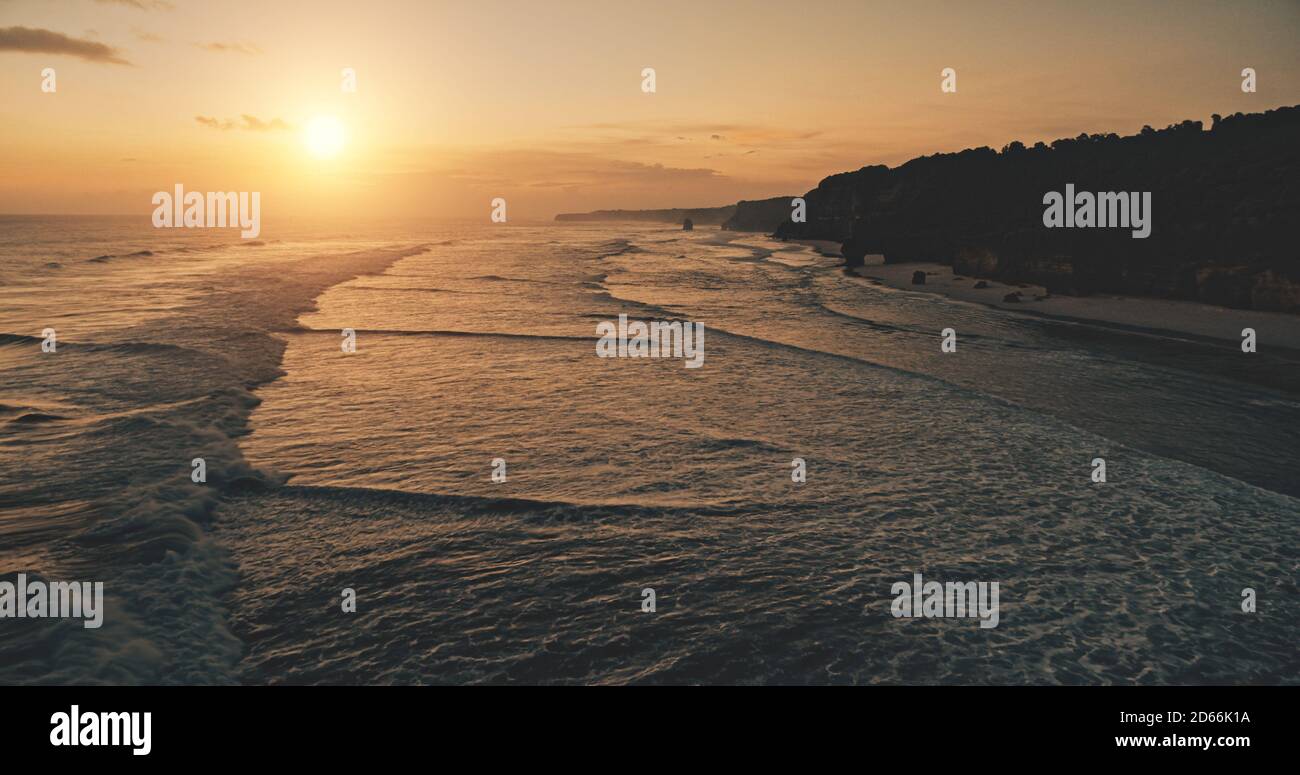 Meereslandschaft bei Sonnenuntergang Licht mit Klippe Küste Silhouette Luftbild. Dunkles Felsenmeer, Sandstrand der Sumba Insel, Indonesien. Niemand Naturlandschaft tropisches Paradies Resort. Drohnenaufnahme im Kino Stockfoto
