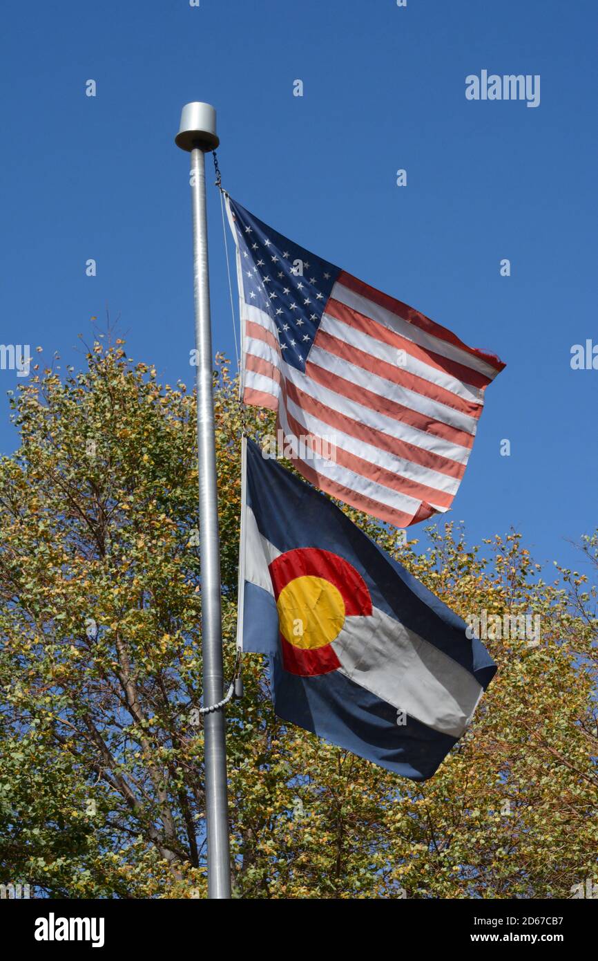 Amerikanische Flagge und Colorado Staatsflagge auf einem Fahnenmast und Winken in der Brise Stockfoto