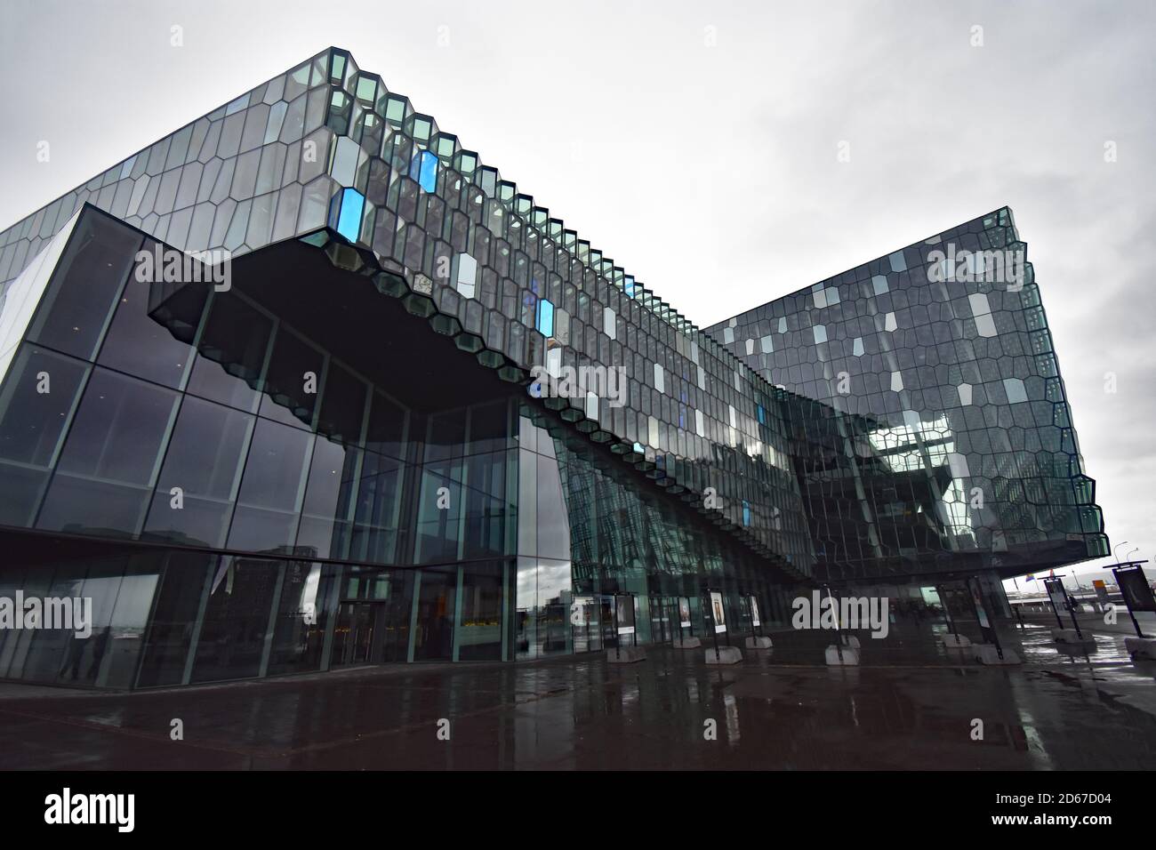 Die markante moderne Architektur der Harpa-Konzerthalle und des Konferenzzentrums in Reykjavik, Island. Draußen gibt es eine kleine Fotokunst-Ausstellung. Stockfoto