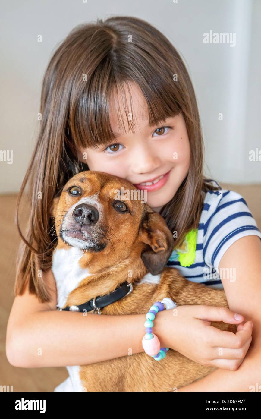 Portrait eines achtjährigen Mädchens, das ihren Hund umarmt Stockfoto