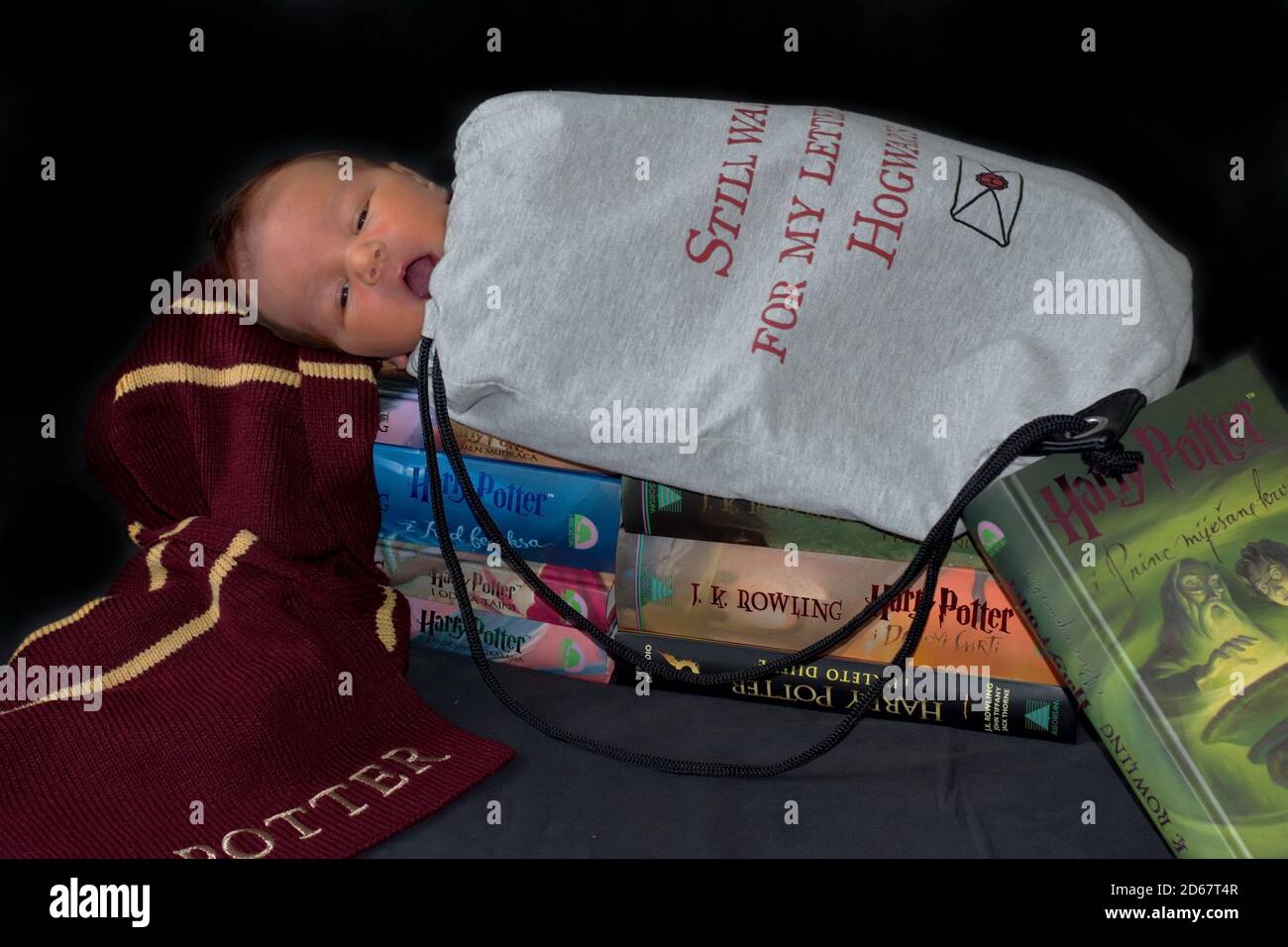 Neugeborener Junge im Kostüm für Halloween mit einem Schal Und Bücher von Harry Potter Stockfoto