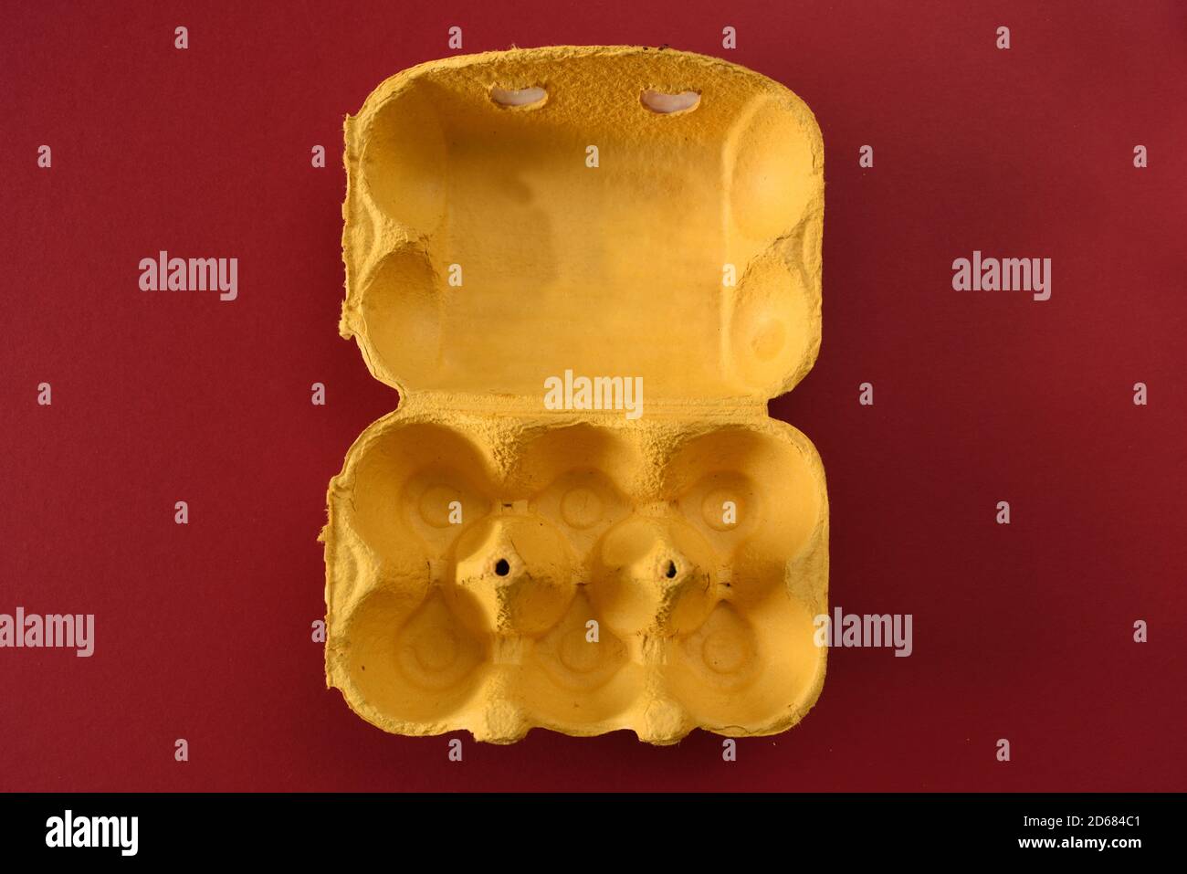 Leerer gelber Eierkarton auf rotem Hintergrund Stockfoto