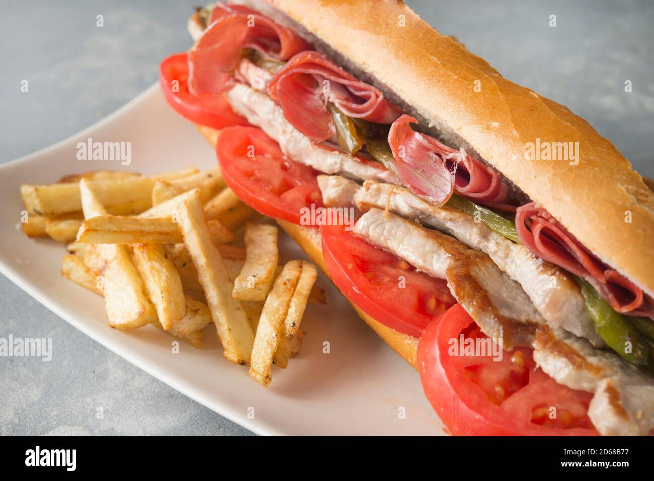 Sandwich Serranito typisch in Andalusien mit Schinken, gren Pfeffer und gegrilltem Schweinefleisch Lende Stockfoto