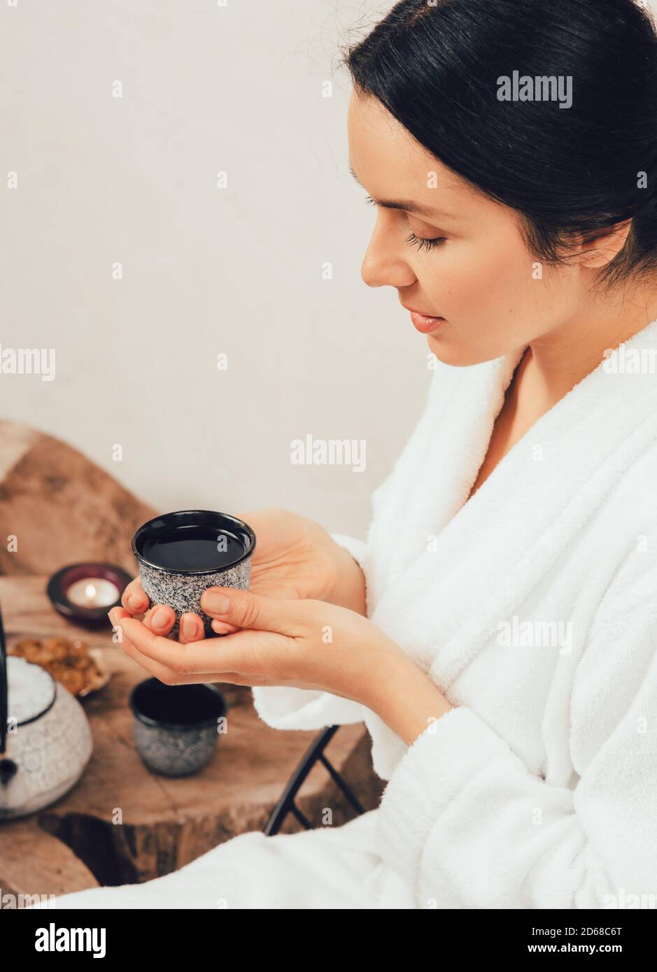 Eine gesunde 35-jährige Frau entspannt und trinkt Tee in einem Bademantel während Wellness-Wochenende Stockfoto