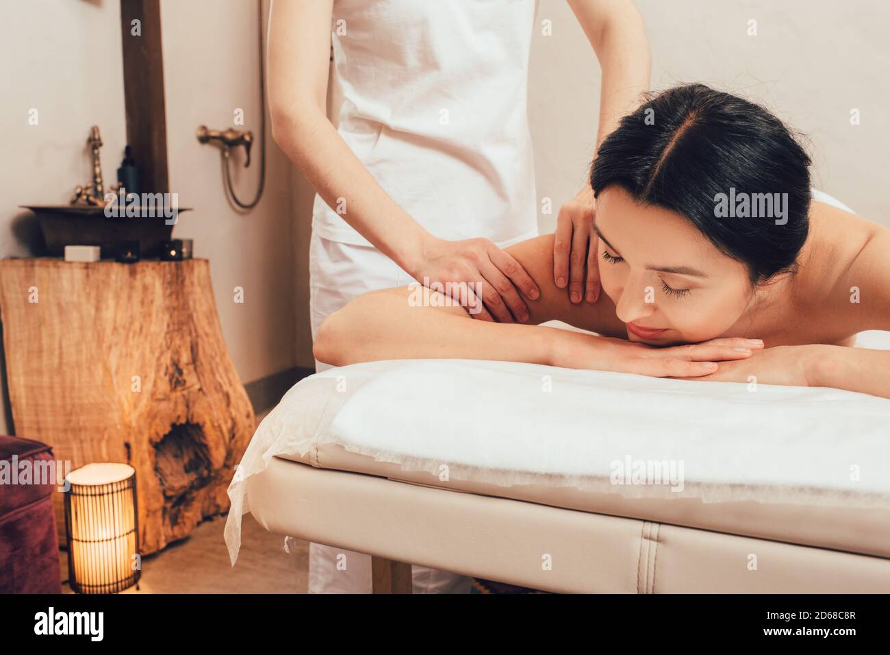 Schöne Frau mit gemischter Rasse genießt eine Rückenmassage in einem orientalischen Spa. Thai Körpermassage, Aromamassage Stockfoto