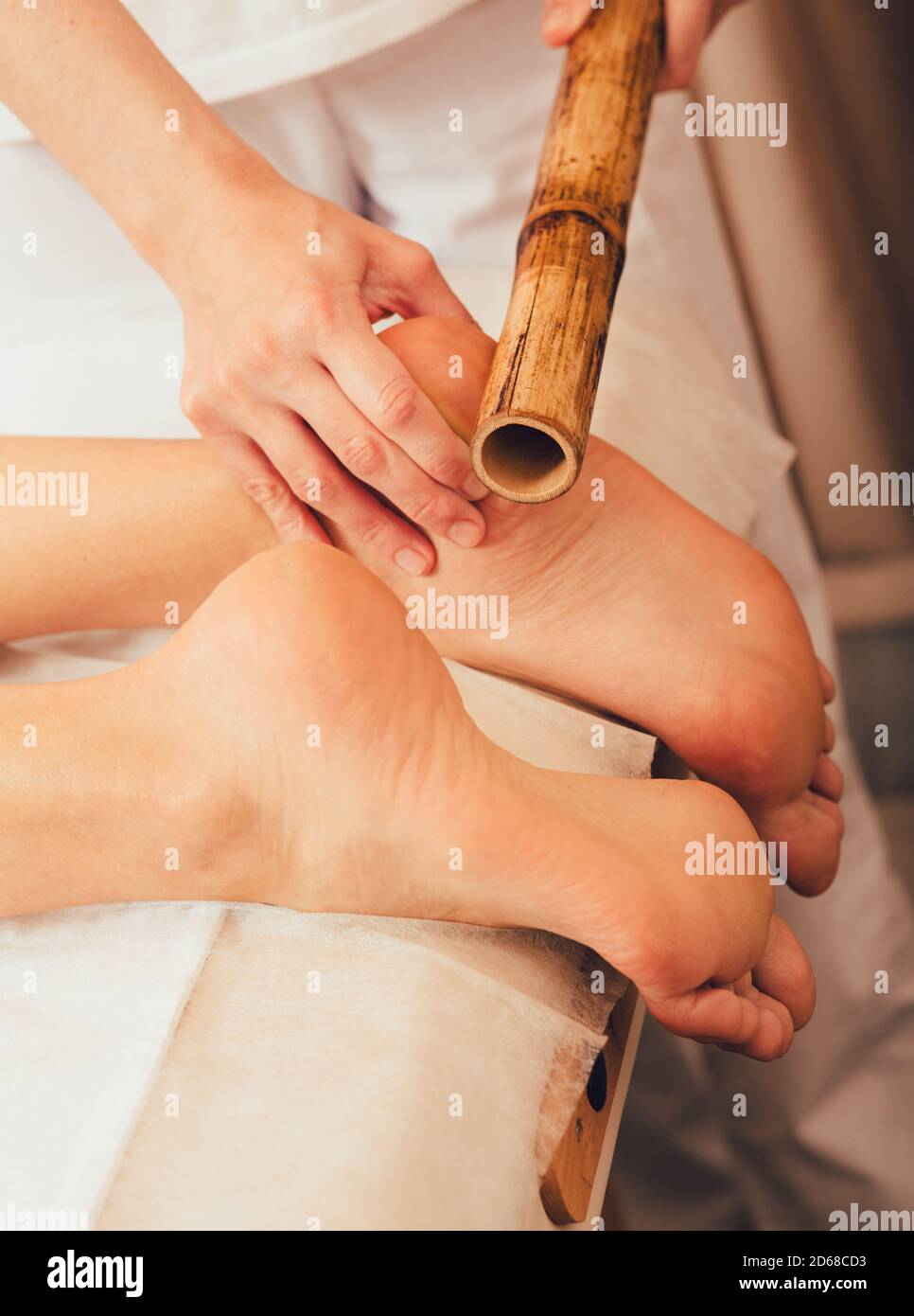 Fußmassage mit Bambusstäben. Massagetherapeut, der thai-Massage mit Bambusstäben durchführt Stockfoto