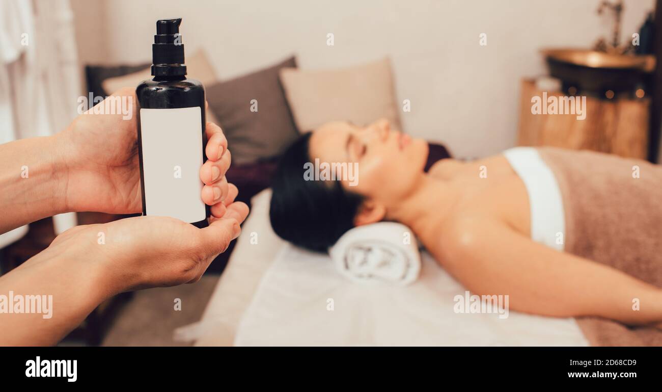Ayurvedische Massage mit Aromaölen. Thai Körpermassage, Aroma Entspannung. Massage Öl Nahaufnahme, schöne Frau in weichen Fokus Stockfoto
