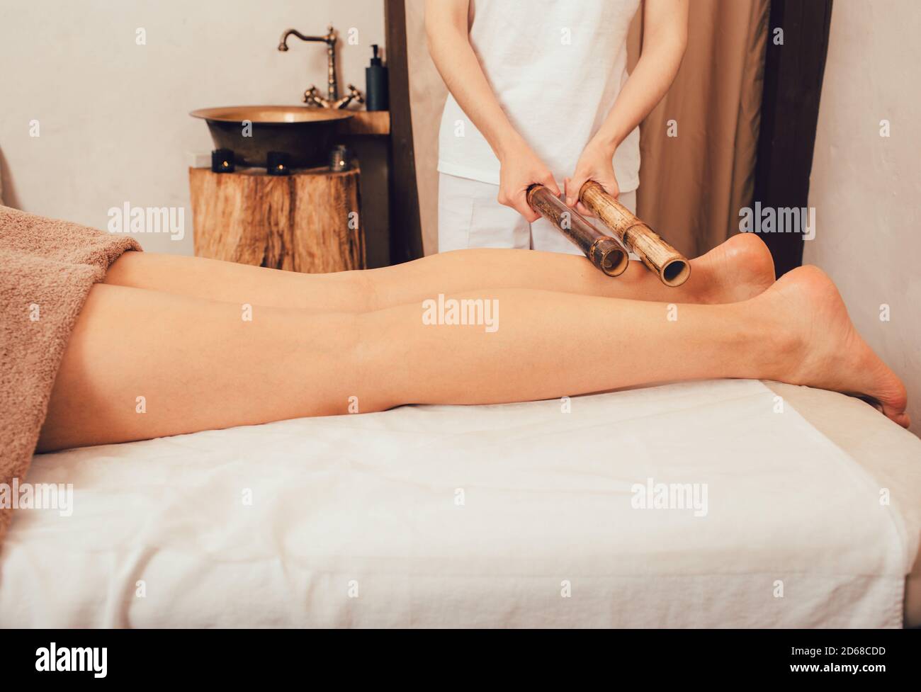 Beinmassage mit Bambusstäbchen. Massagetherapeut, der thai-Massage mit Bambusstäben durchführt Stockfoto