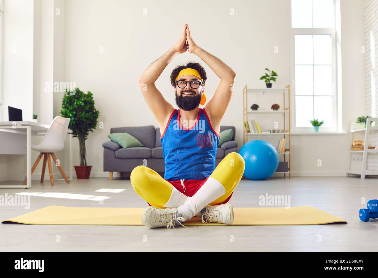 Lustiger Mann sitzt in leichter Yoga-Pose mit erhobenen Armen, lernen, Atemübungen zu tun und zu meditieren Stockfoto