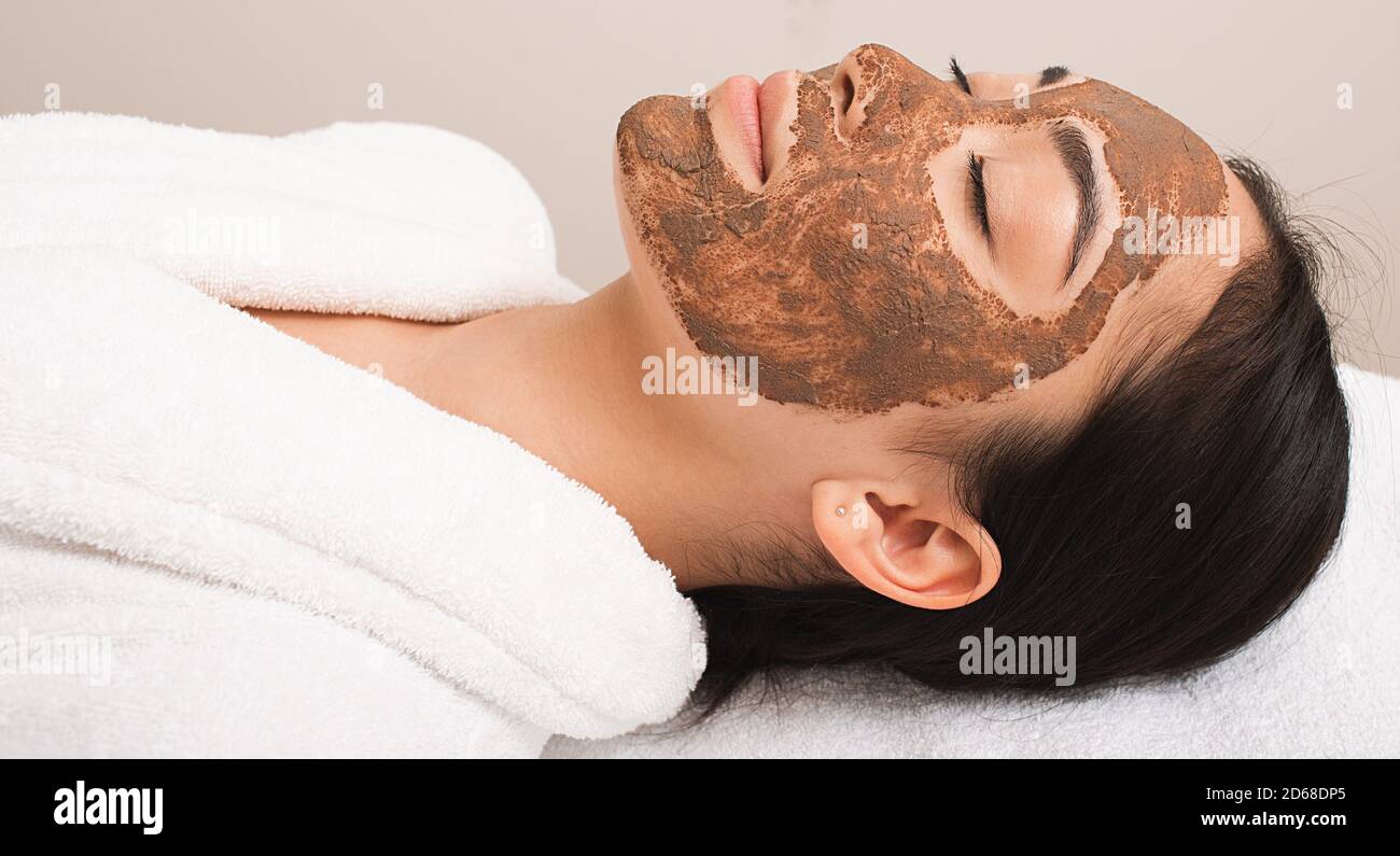 Frau mit einer Schlammmaske im Gesicht. Behandlung, Reinigung und Erweichung der Gesichtshaut. Schlammbehandlung Stockfoto