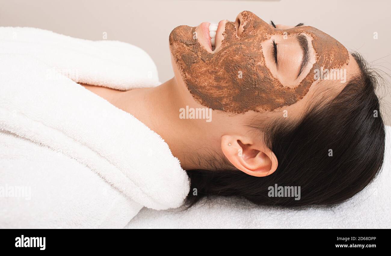 Frau mit einer Schlammmaske im Gesicht. Behandlung, Reinigung und Erweichung der Haut. Teil einer Serie mit Schlammmaske Stockfoto