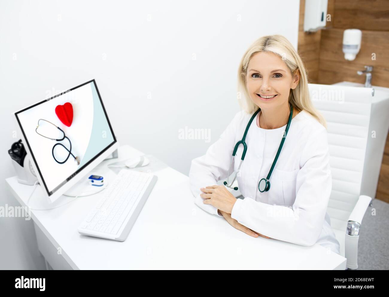 Porträt der reiferen Arztpraztin am Arbeitsplatz. Arzt mit Stethoskop, sitzt in einer Arztpraxis Stockfoto