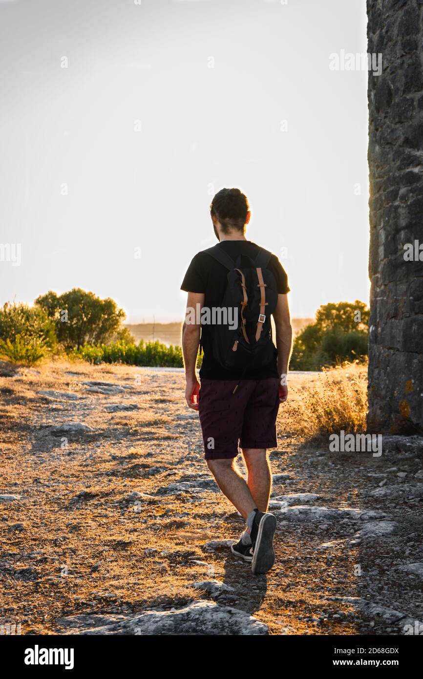 Mann, der mit einem Rucksack zum Sonnenuntergang läuft Stockfoto