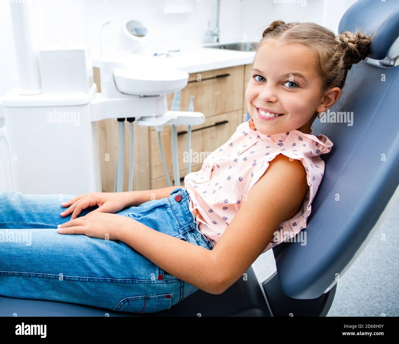 Kind lächelt, während es auf dem Zahnarztstuhl sitzt. Zähnebehandlung für Kinder Stockfoto