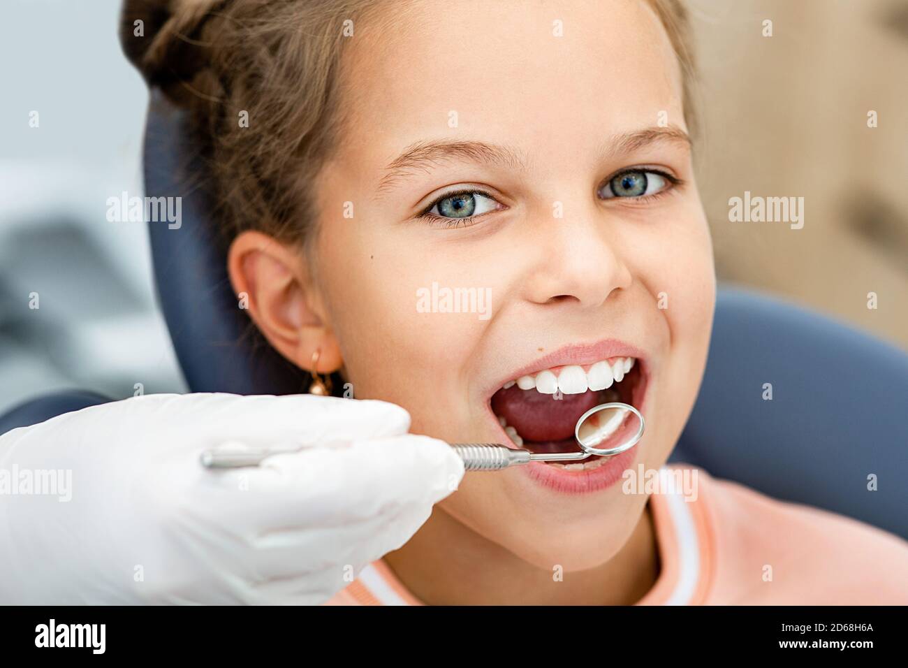 Kleines lächelndes Mädchen, Zähne Check-up. Zahnuntersuchung mit Zahnspiegel Nahaufnahme. Zahnbehandlung für Kinder Stockfoto