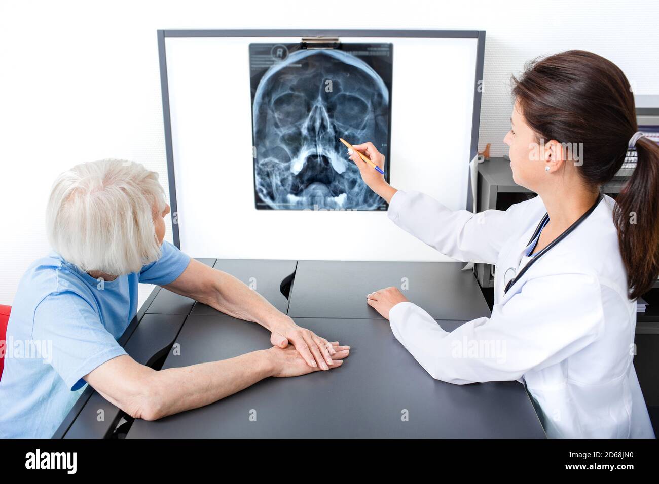 Der Arzt erwägt und bespricht mit einer älteren Patientin eine Röntgenaufnahme ihres Kopfes und der Kieferhöhlen. Diagnostik und Therapie der Sinusitis und der Sinusitis frontalis Stockfoto