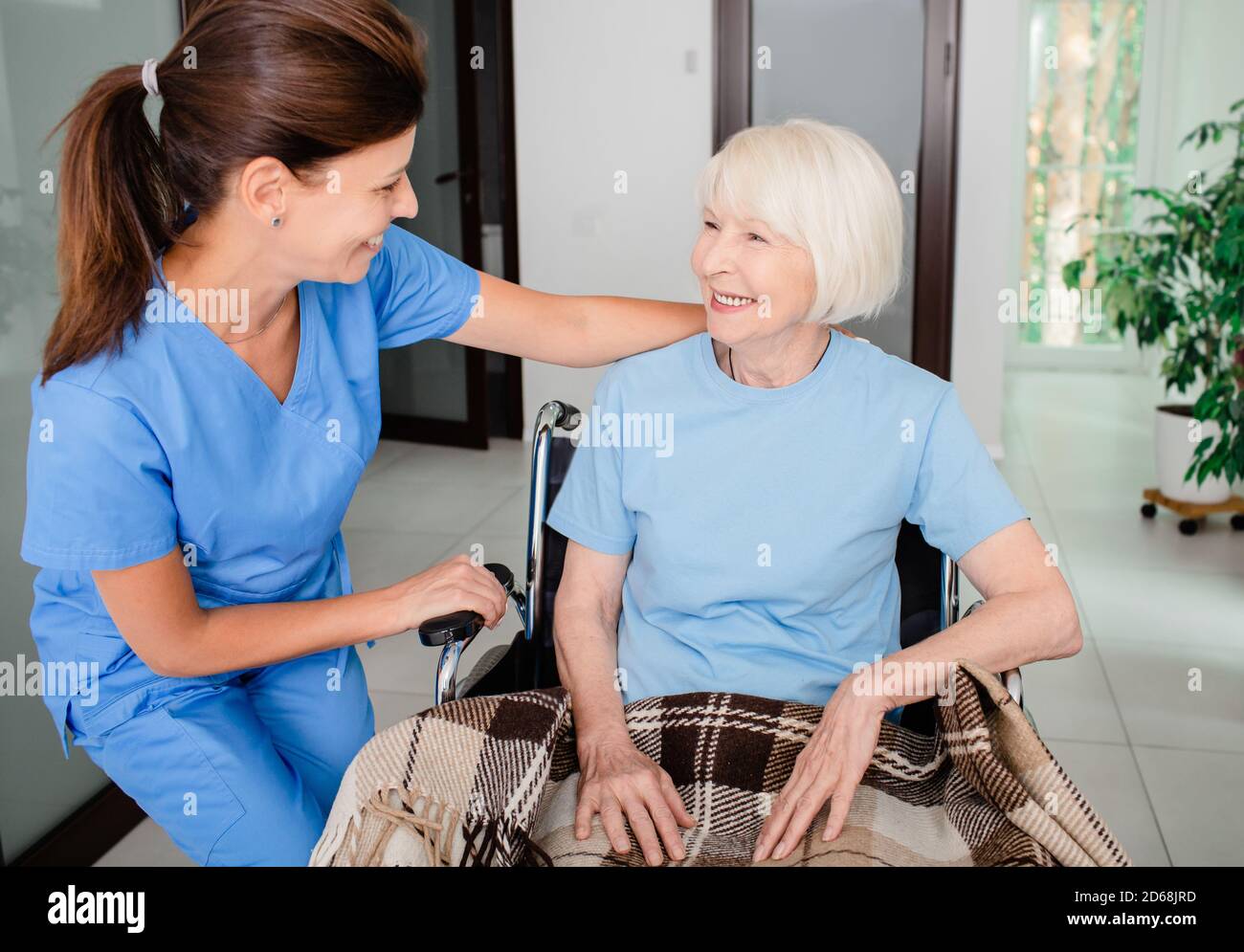 Psychologische Unterstützung, eine Krankenschwester und eine ältere Frau im Rollstuhl haben Kommunikation. Pflege von Menschen mit Behinderungen Stockfoto