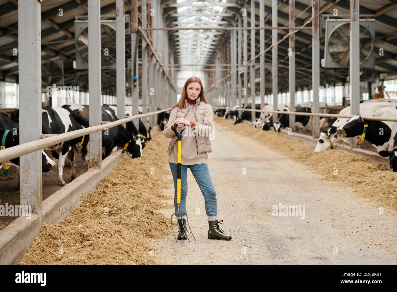 Portrait einer seriösen selbstbewussten Farm Frau, die mit einer Pitchfork im Stehen steht Moderner Kuhstall Stockfoto